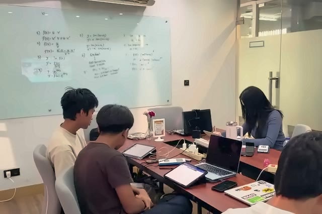 Students work through problems with the board behind them